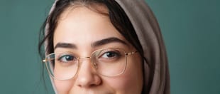 پرتره‌ی نزدیک زنی جوان با عینک و روسری، در پس‌زمینه‌ای سبز